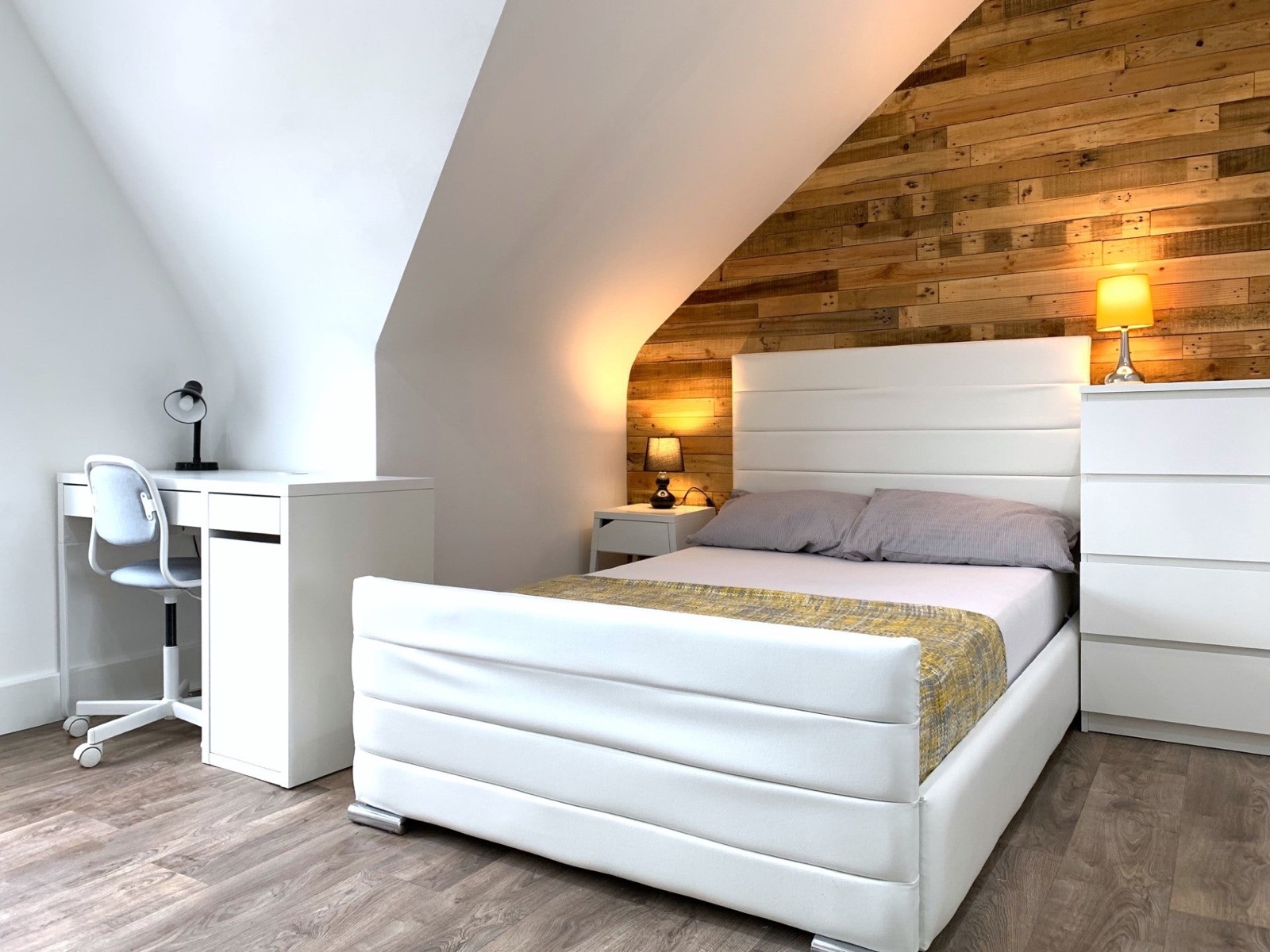 Cosy double bedroom under a sloped ceiling with a timber feature wall